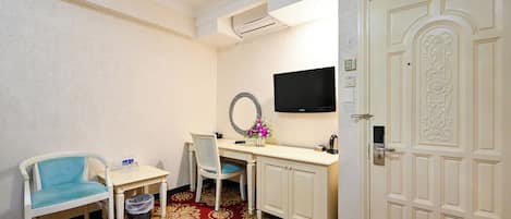 Una habitación de hotel con un escritorio, una silla, un televisor y una puerta.