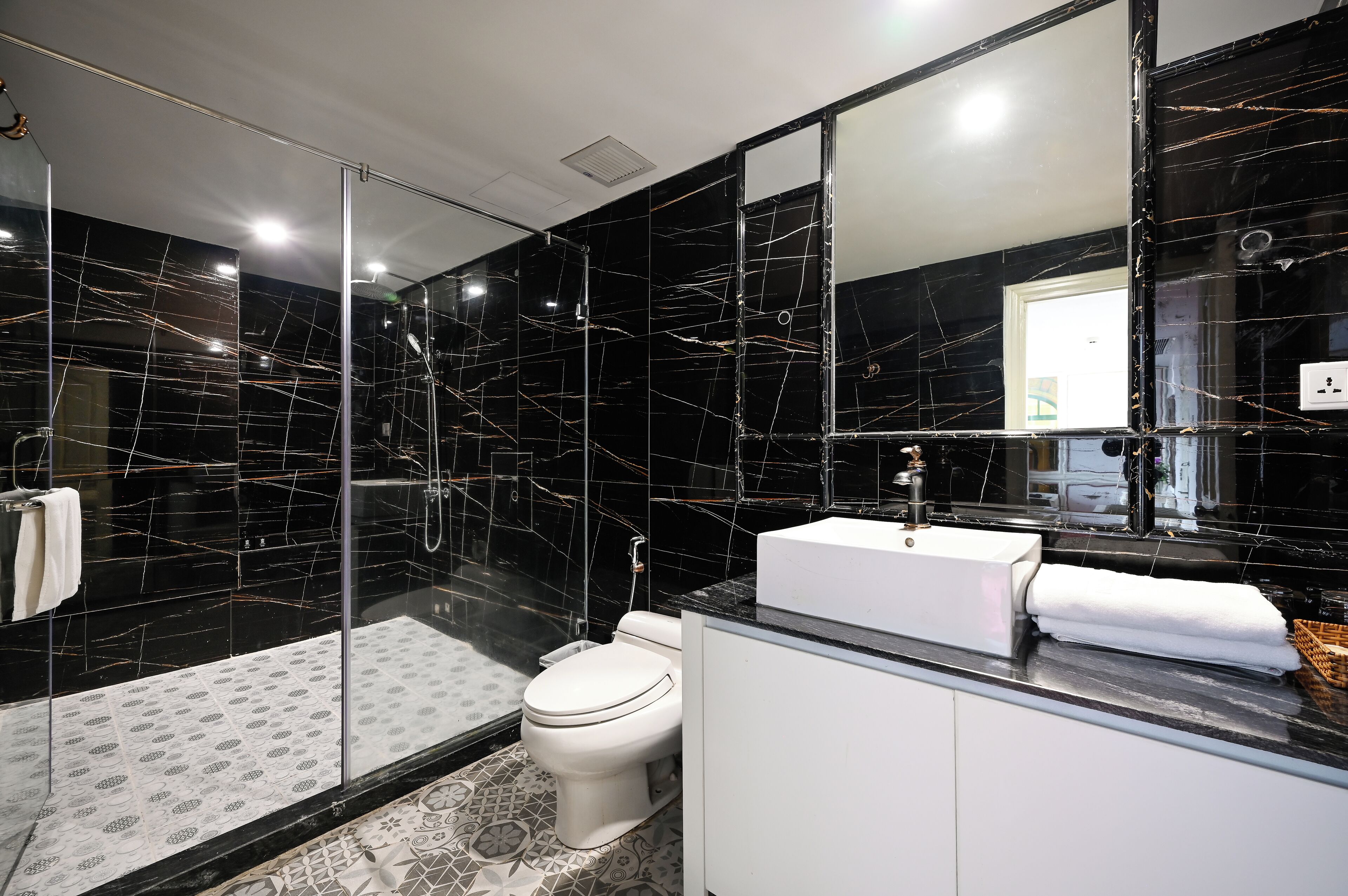 A modern bathroom with a glass-enclosed shower, a white toilet, and a vanity with a sink and mirror.