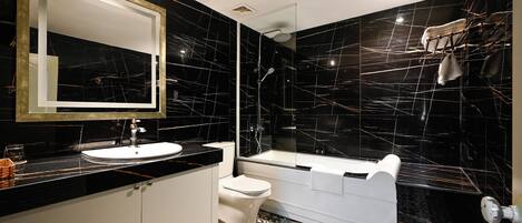 Ein modernes Badezimmer mit Schwarz-Weiß-Marmor-Design, einem großen Spiegel, einem Waschbecken, einer Toilette und einer Badewanne.