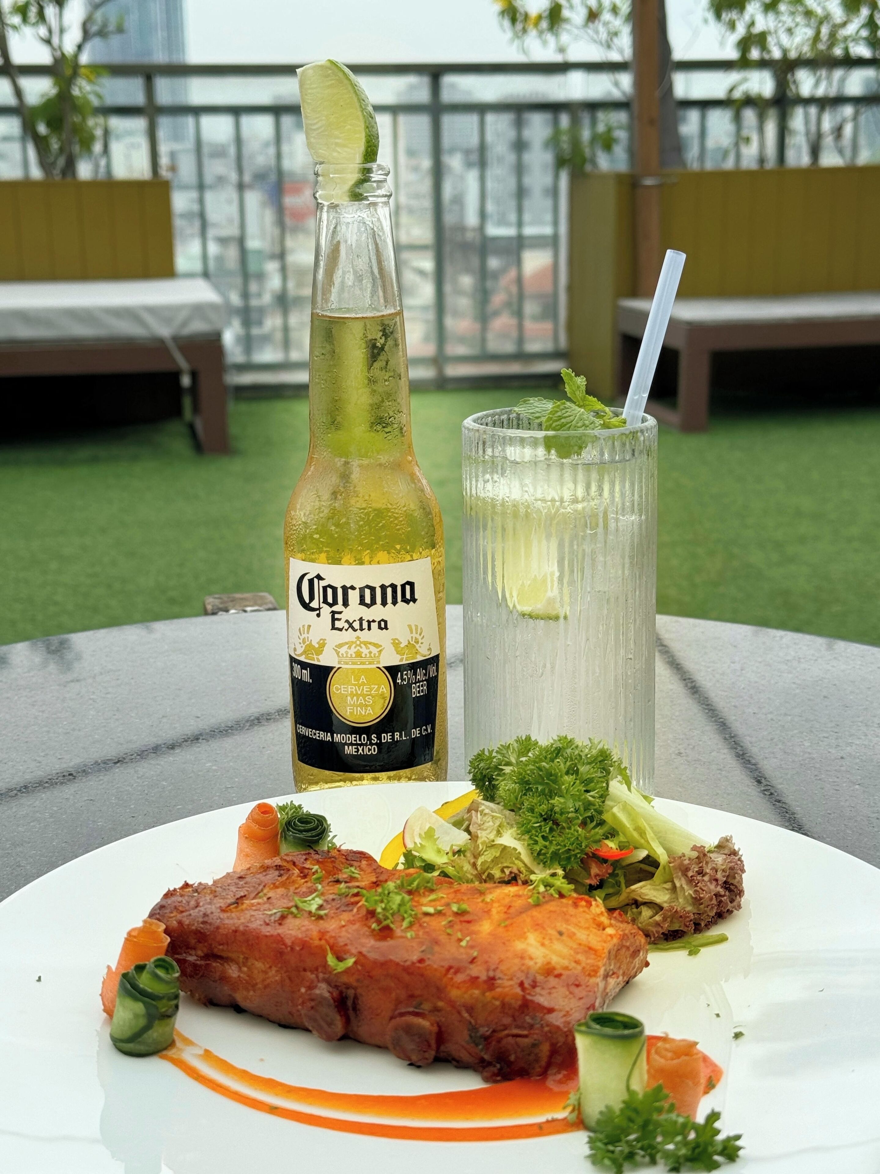 A meal with a bottle of Corona Extra beer and a glass of beer on a table.