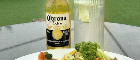A meal with a bottle of Corona Extra beer and a glass of beer on a table.
