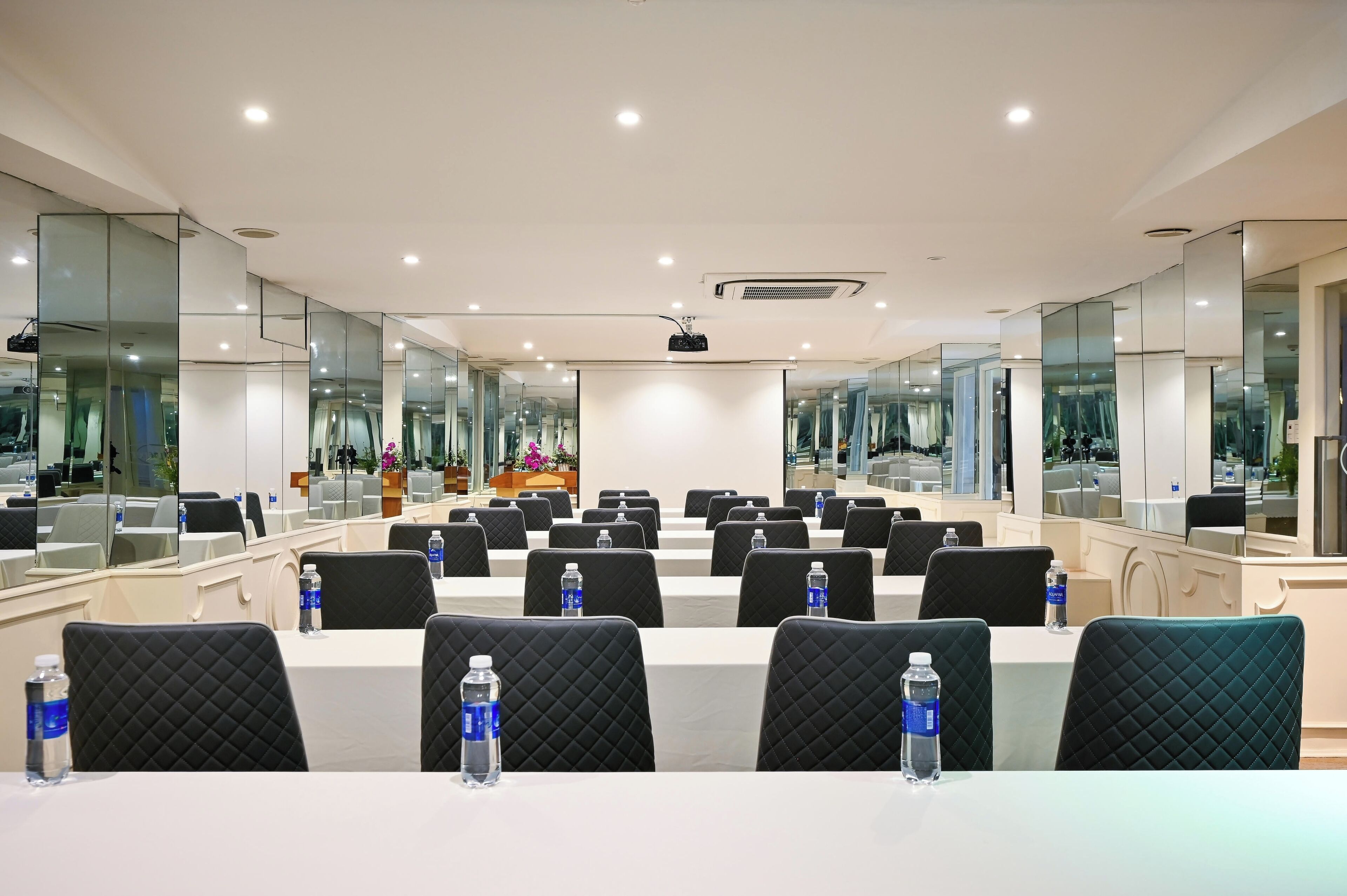 Una sala de conferències amb diverses taules, cadires i un projecte.
