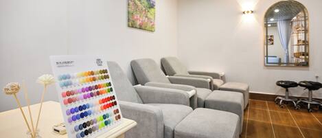 A room with grey cushioned chairs, a color palette chart, a mirror, and a ceiling with a geometric pattern.
