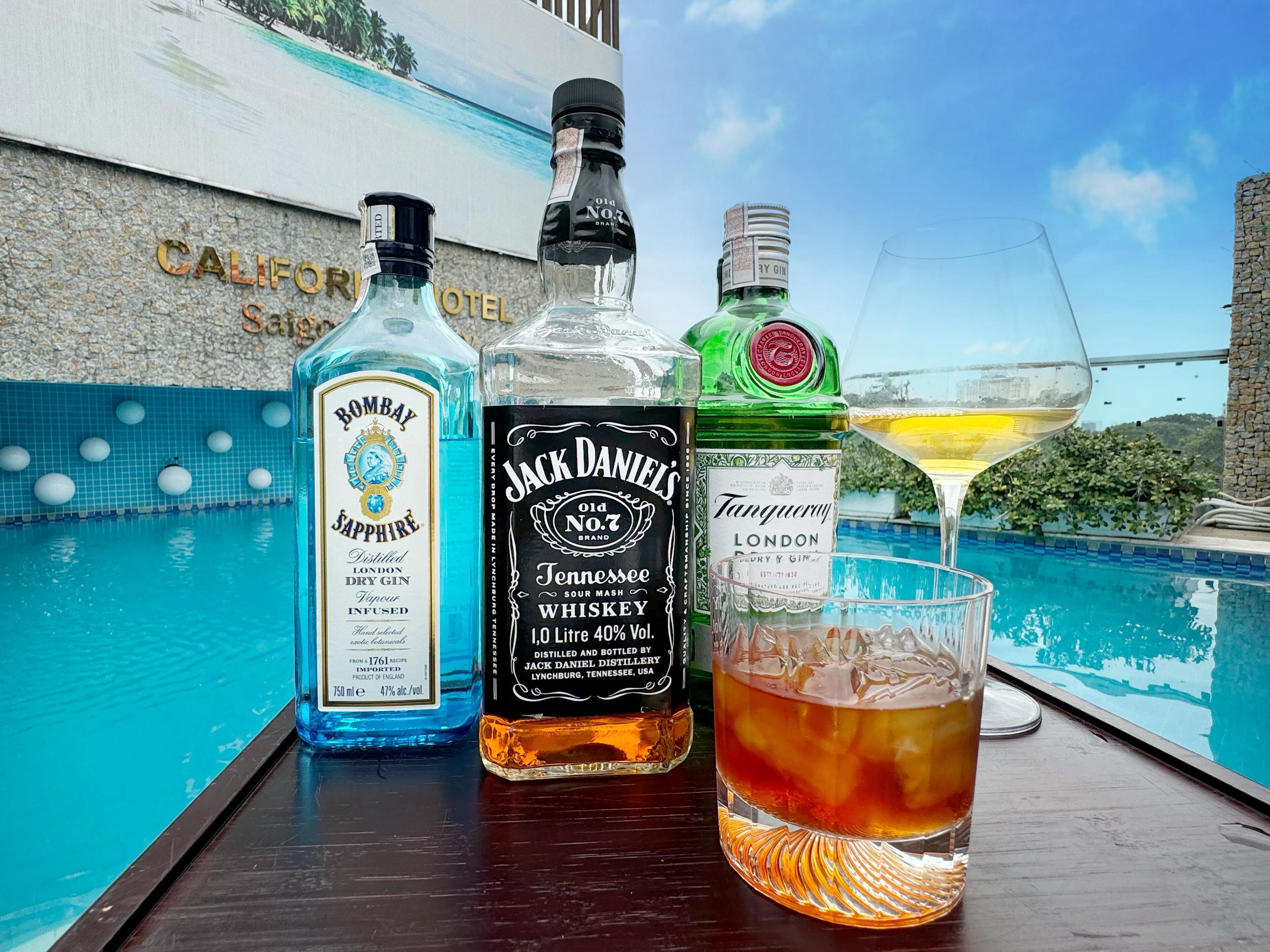 Egy medenceparti hangulat, Bombay Sapphire ginből, Jack Daniel's whiskyből és Tanqueray London ginből álló üvegekkel, valamint egy pohár whiskyvel.