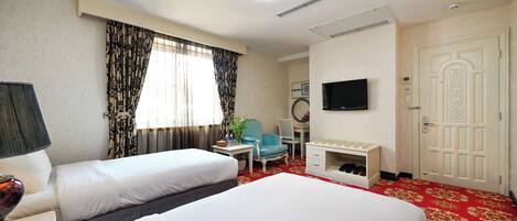 A hotel room with two beds, a desk, a chair, a television, and a wardrobe.