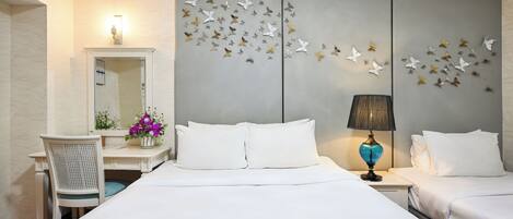 Una camera d'albergo con un letto grande, due comodini, una scrivania con una sedia, uno specchio e un quadro raffigurante farfalle.