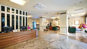 Un hall de hotel con una recepción, computadoras, máquinas expendedoras y zonas de estar.