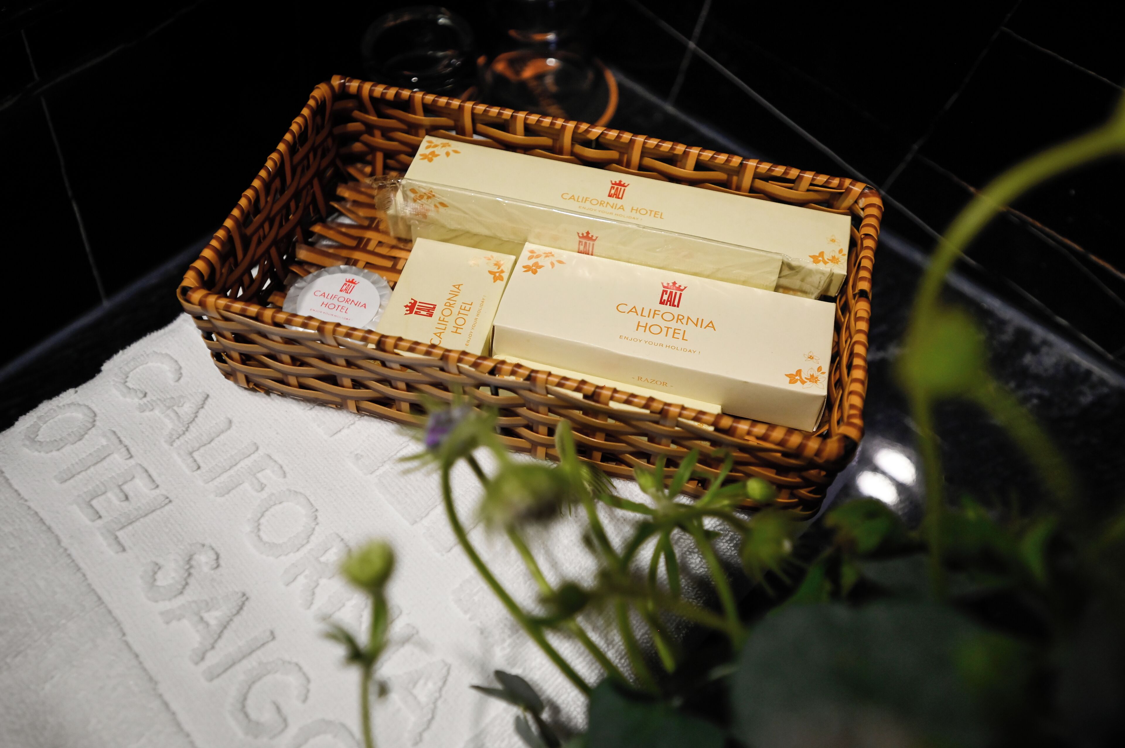 A wicker basket containing toiletries and a towel with "CALIFORNIA HOTEL" printed on it.