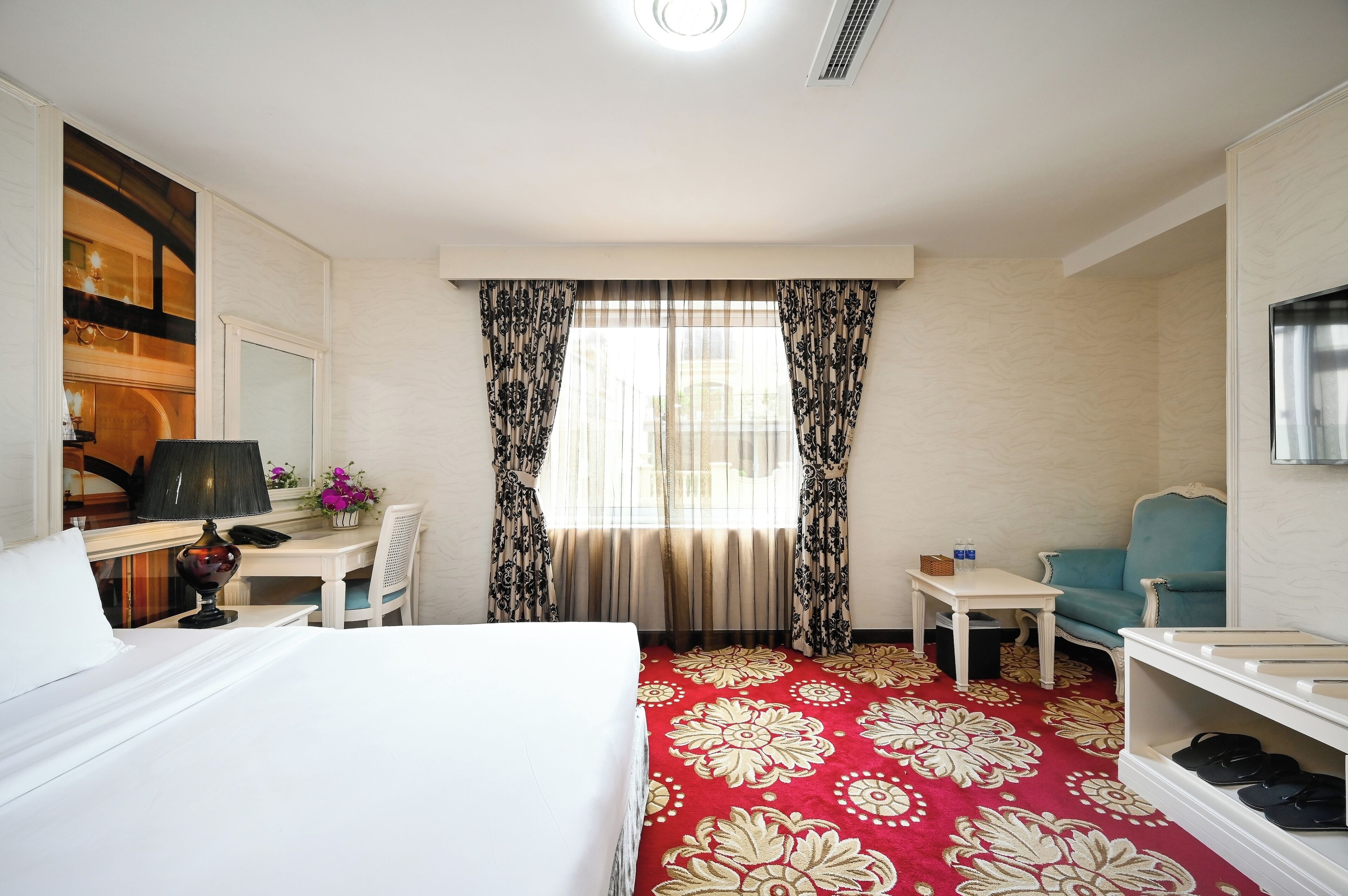 A hotel room with a bed, desk, chair, and a TV.