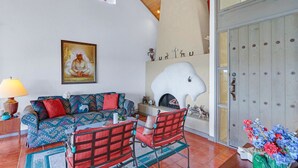 Una sala de estar con sofá, sillones, chimenea y un detalle decorativo en la pared.