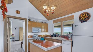 Una cocina con armarios de madera, una isla central, un refrigerador y un ventanal con vistas.