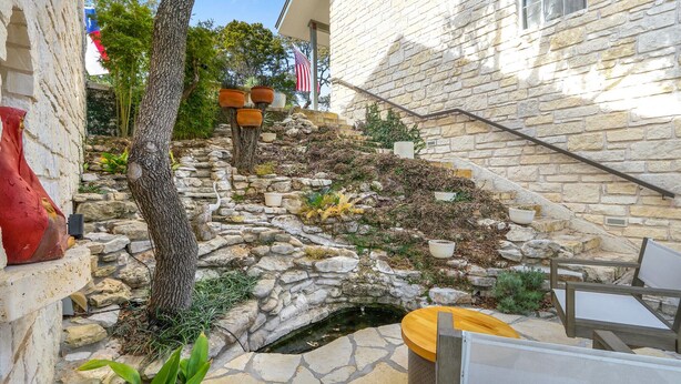 A stone staircase leading to a house with a small garden area, outdoor furniture, and a flag. - White Buffalo Room With a View I Stargazing, Romantic (Wimberley)