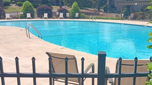 Ein Schwimmbecken mit Liegestühlen und einem Zaun.