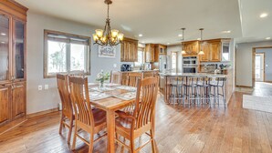 Una cocina amplia con armarios de madera, un comedor con candelabro y una isla grande con taburetes de bar.