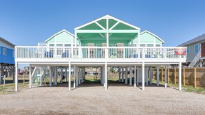 A two-story building with a covered balcony and a staircase leading to the upper level. - Great for Groups: Oceanfront Surfside Beach Home! (Freeport)