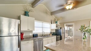A modern kitchen with stainless steel appliances, white cabinetry, and a granite countertop. - Great for Groups: Oceanfront Surfside Beach Home! (Freeport)