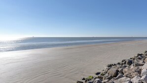A beach with a rocky shoreline and calm water. - Great for Groups: Oceanfront Surfside Beach Home! (Freeport)