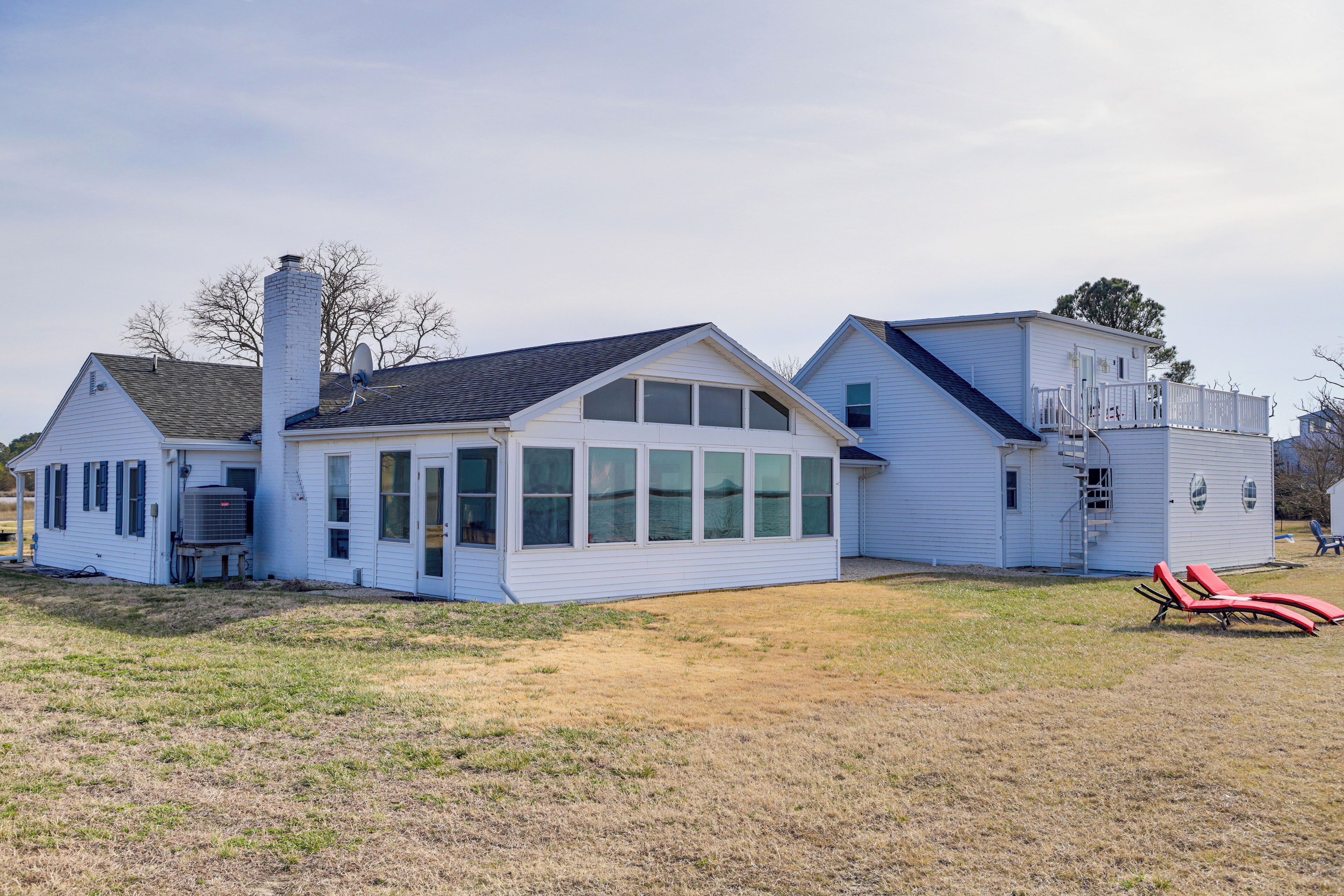 A two-story house with a large front porch, a chimney, and a satellite dish.