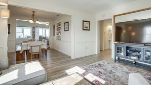A spacious living area with a large flat-screen TV, a dining table with chairs, and a cozy seating area with a patterned rug.