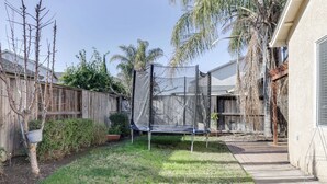 A backyard with a trampoline, a wooden fence, and a house. - Spacious Turlock Home ~ 1 Mi to University! (Turlock)