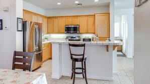 A modern kitchen with wooden cabinets, stainless steel appliances, and a breakfast bar. - Spacious Turlock Home ~ 1 Mi to University! (Turlock)
