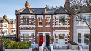 A two-story brick house with a red door, white trim, and a black and white tiled entrance. - Stylish River Apartment - West Putney Embankment (London)