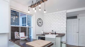 A kitchen with a wooden countertop, a sink, a clock, and a window with a view of the outside. - Stylish River Apartment - West Putney Embankment (London)