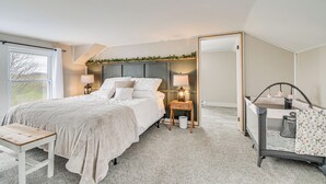 A bedroom with a bed, bedside tables, a nightstand, a crib, and a large mirror. - Auburn Finger Lakes Farmhouse w/ Open Views! (Auburn)