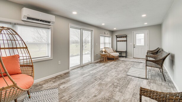 A spacious room with a large window, wicker chairs, and a ceiling fan. - Auburn Finger Lakes Farmhouse w/ Open Views! (Auburn)