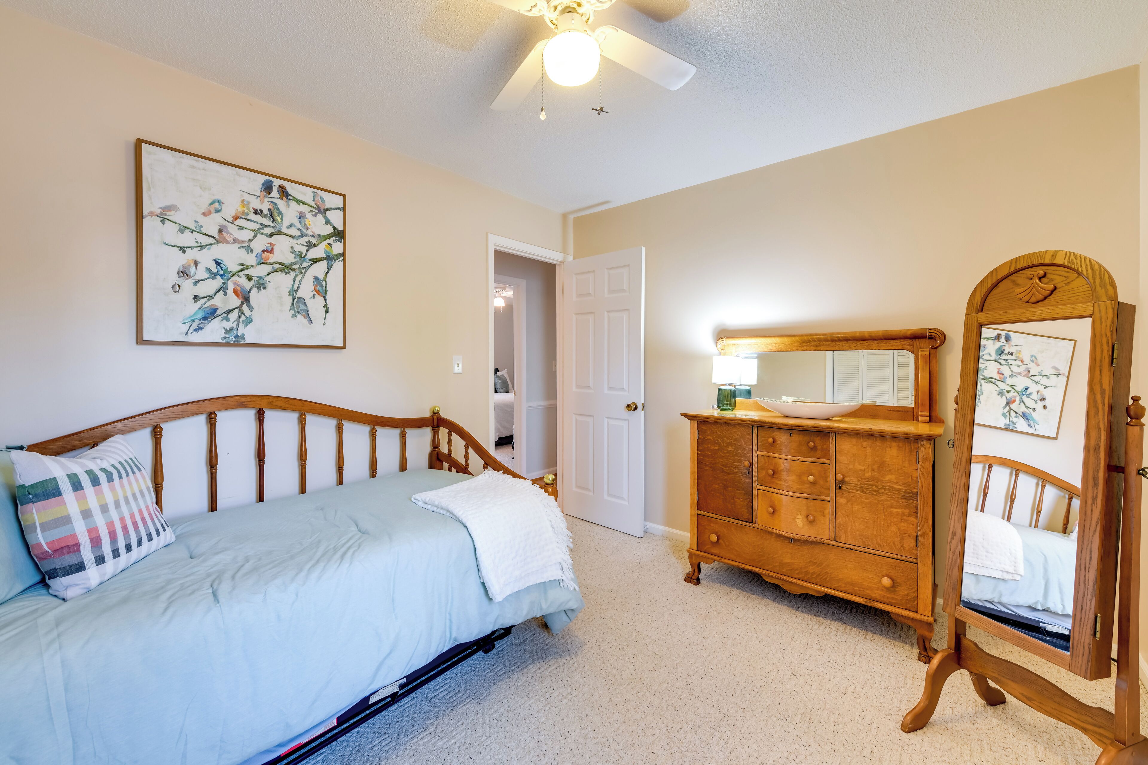 A bedroom with a bed, dresser, and a mirror.