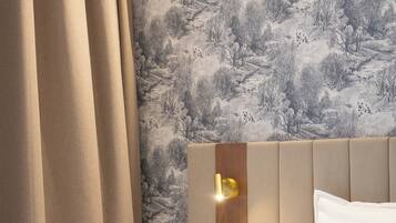 A hotel room with a bed, a nightstand, a cup, and a wall-mounted light fixture.
