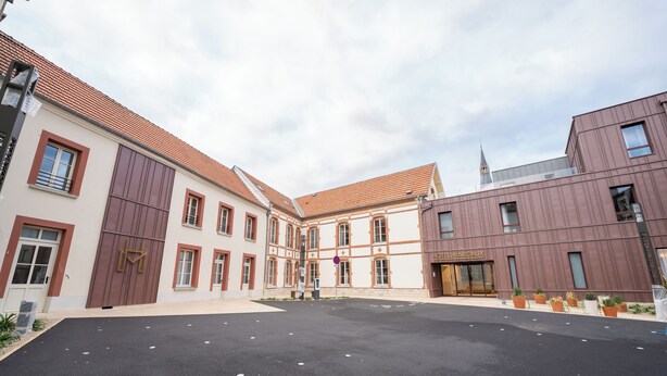 A courtyard with a modern building featuring large windows and a traditional building with a tiled roof. - Hôtel Margaux  (Epernay)