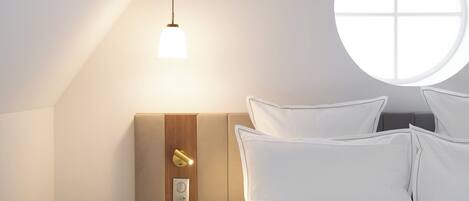 Een slaapkamer met een bed, nachtkastje, lamp en raam.