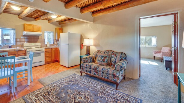 A spacious kitchen with wooden beams, a dining area with a blue chair, and a patterned sofa. - Quiet Mora Hideaway: 35 Mi to Angel Fire Resort! (Mora)
