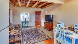 A living room with a sofa, TV stand, dining table, and a rug. - Quiet Mora Hideaway: 35 Mi to Angel Fire Resort! (Mora)