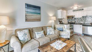 A living room with a beige sofa, a coffee table, and a painting of a beach scene. - Hilton Head Island Condo w/ Coligny Beach Access! (Hilton Head Island)