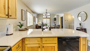 A kitchen with wooden cabinets, a white countertop, a built-in dishwasher, and a chandelier. - Nisswa Townhome w/ Boat Slip + Gull Lake Access! (Nisswa)