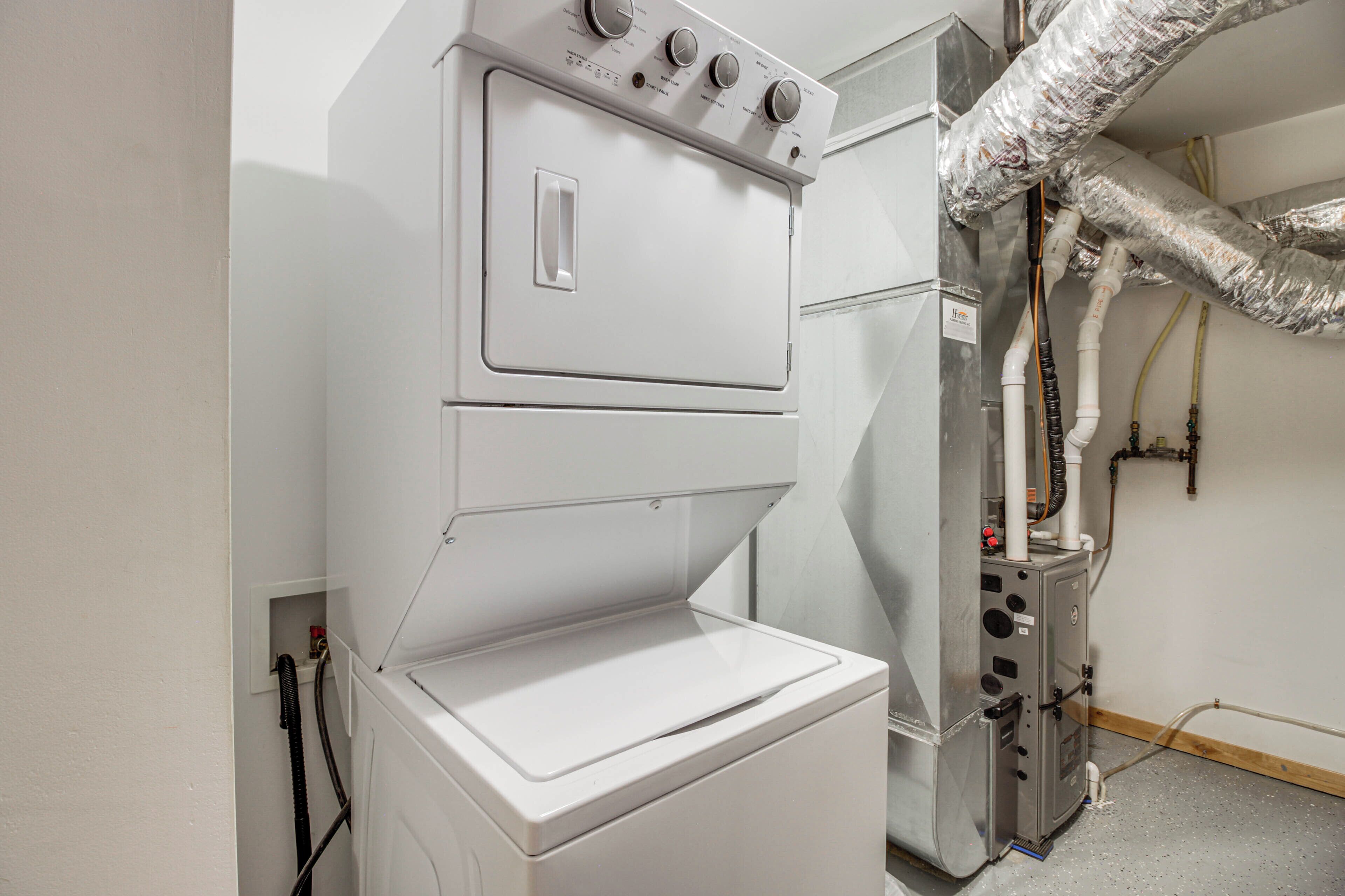 A compact, white laundry room with a built-in washer and dryer, ventilation ducts, and a control panel.
