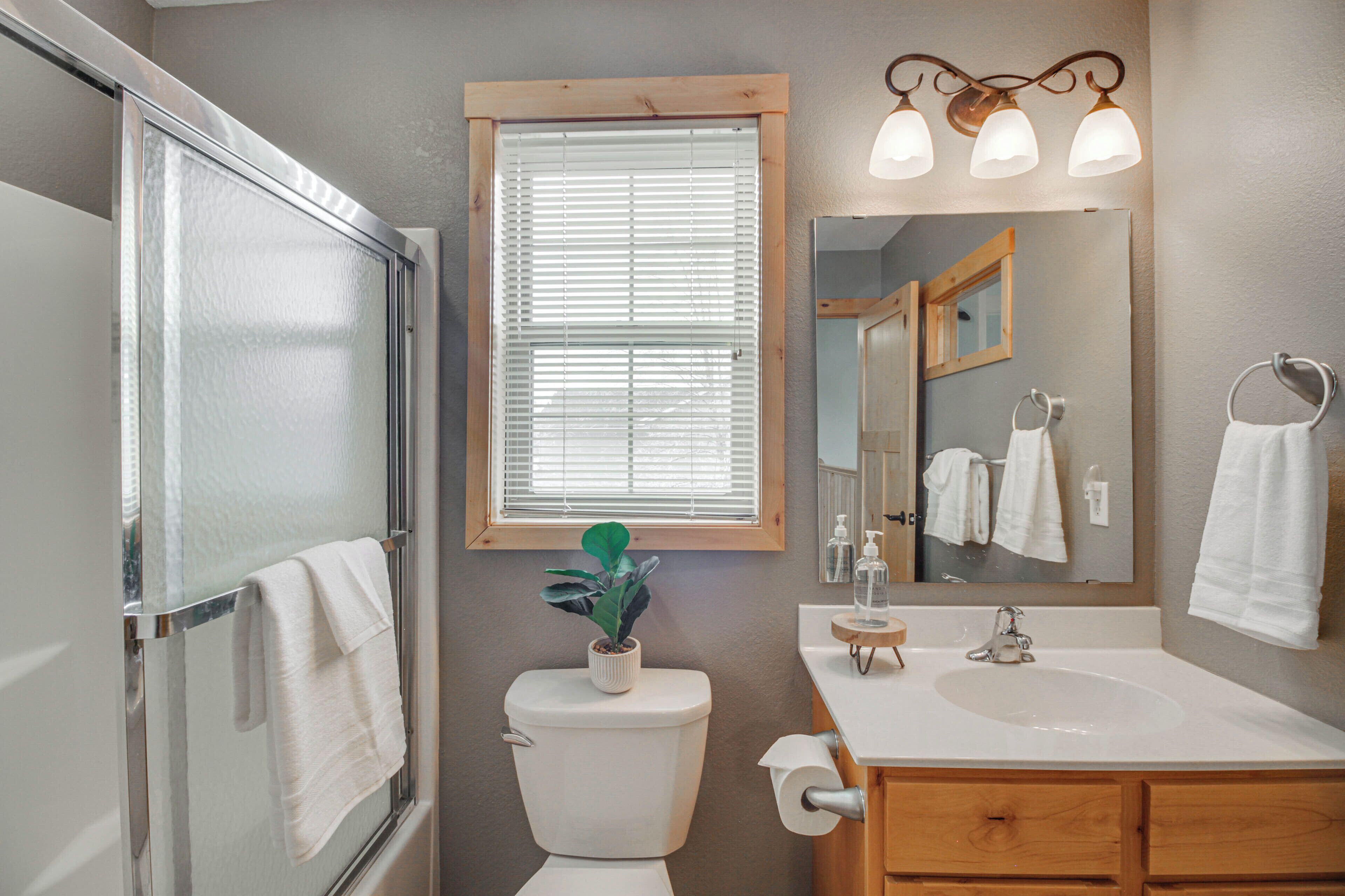 Une salle de bain équipée d’une douche, de toilettes, d’un lavabo et d’un miroir avec un porte-serviettes.