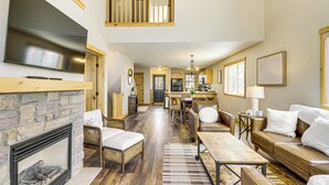 A spacious living area with a fireplace, seating, a television, and a kitchen in the background. - Nisswa Townhome w/ Boat Slip + Gull Lake Access! (Nisswa)