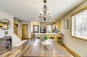 A spacious kitchen with wooden flooring, a central island, and a chandelier.