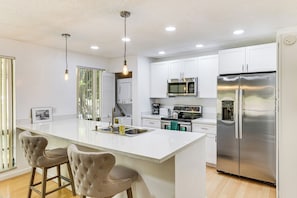 Una cucina moderna con isola centrale, elettrodomestici in acciaio inossidabile e illuminazione a sospensione.