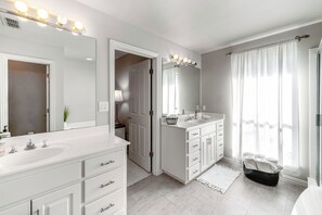 A modern bathroom with a double sink vanity, a large mirror with lights, a walk-in shower, and a view of the outdoors. - ~ 3 Mi to Dtwn: Aubrey Vacation Rental w/ Patio! (Aubrey)