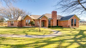 A brick house with a chimney, a front yard, and a clear sky. - ~ 3 Mi to Dtwn: Aubrey Vacation Rental w/ Patio! (Aubrey)