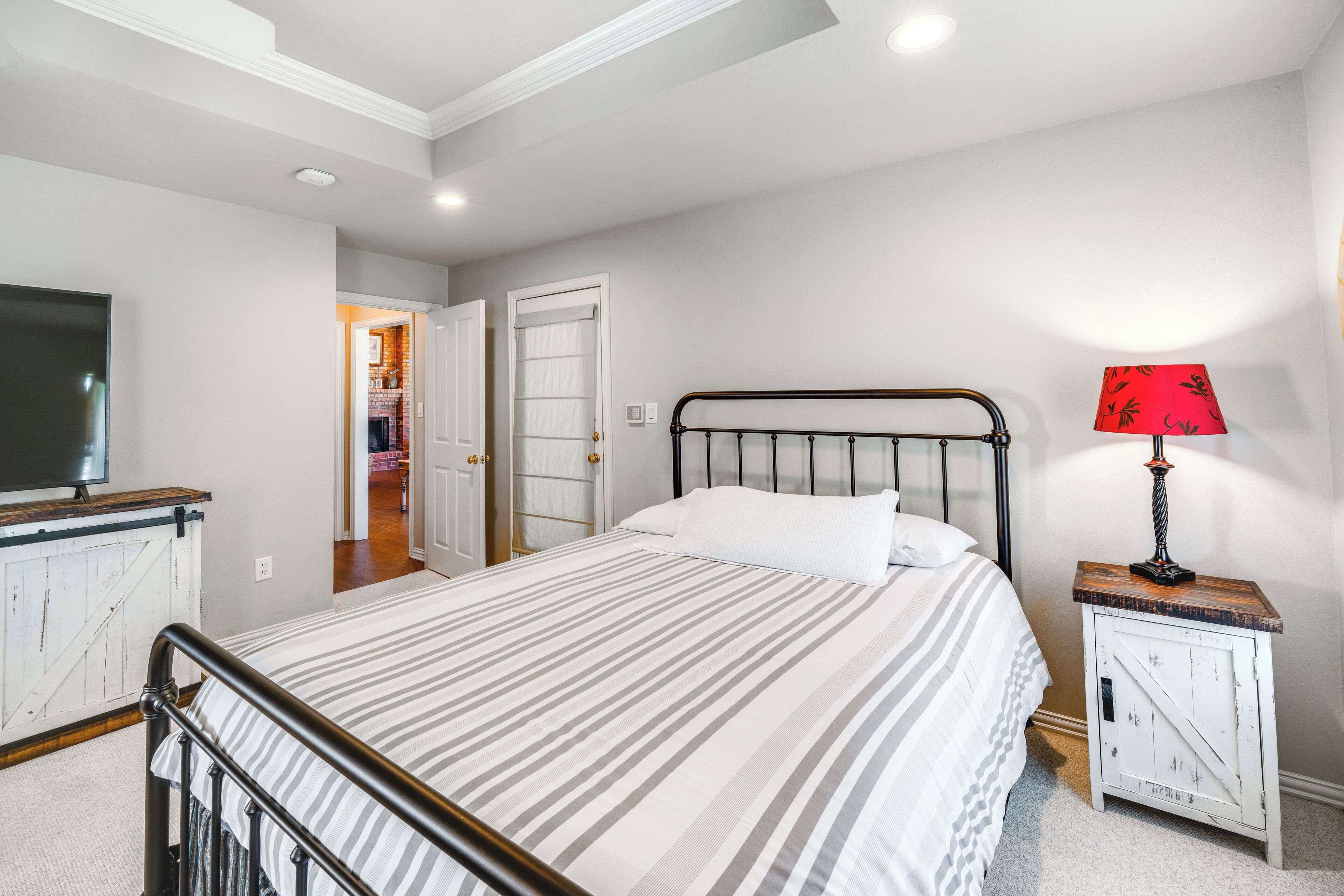 A bedroom with a bed, a TV, a bedside table with a lamp, and a wardrobe.