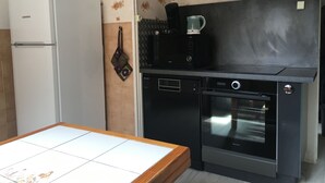 Una cocina compacta equipada con refrigerador, cafetera, lavavajillas y horno.