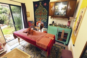A room with a bed, a small cabinet, a radiator, and a window.