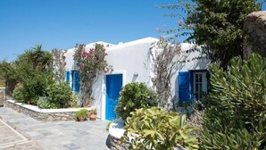 A white building with blue doors and windows, surrounded by greenery and stone walls. - Mykonian Luxury Villa Victoria with Pool (Mykonos)