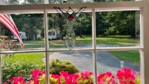 A window with a decorative metal piece and a view of a green landscape with flowers and a road. - Sunny at 135 is a wonderful place to  (Aiken)