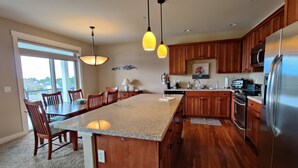 A modern kitchen with wooden cabinets, a large island, and stainless steel appliances. - BP 410 River Song Condo.  3 blocks from the beach (Seaside)